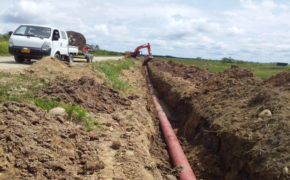 Un camión blanco está estacionado al lado de una tubería roja en la tierra.
