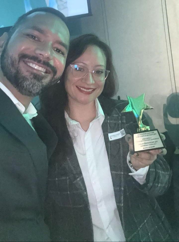 Un hombre y una mujer posan para una fotografía y la mujer sostiene un trofeo.