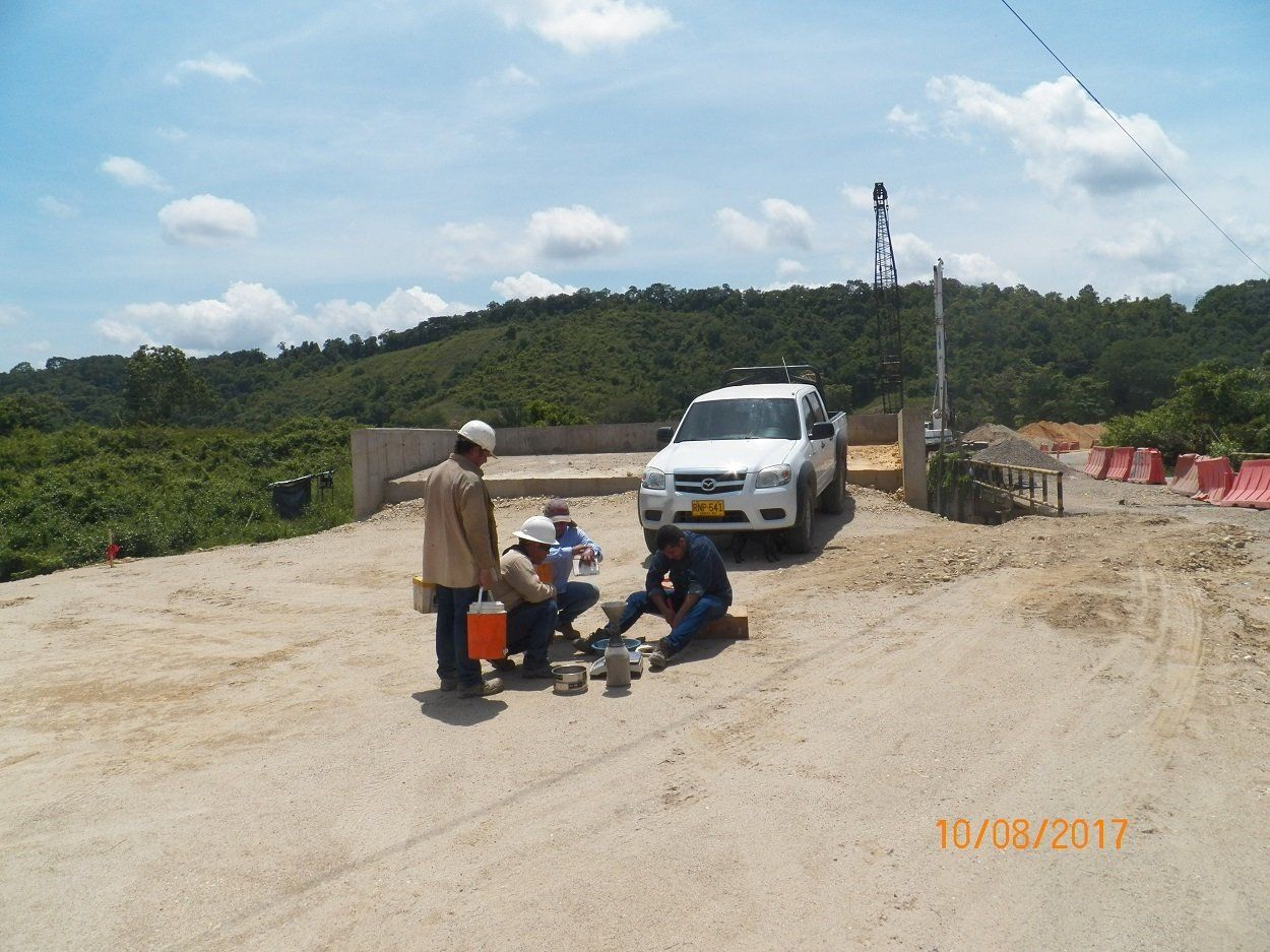 Un grupo de personas está de pie en un camino de tierra al lado de un camión blanco.