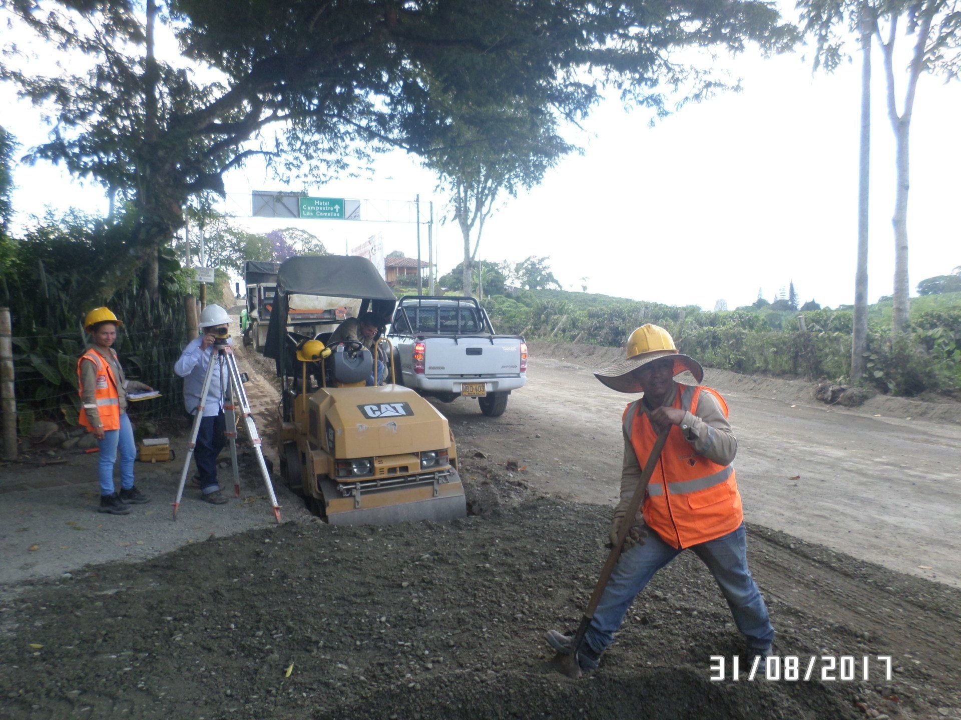 Un hombre con un chaleco naranja está trabajando en una carretera.