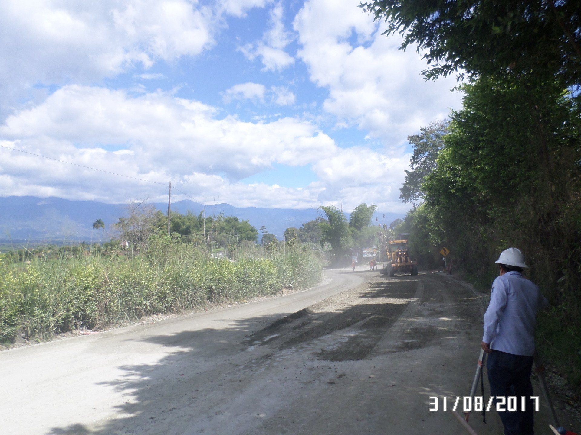 Un hombre que lleva un casco está parado en un camino de tierra.