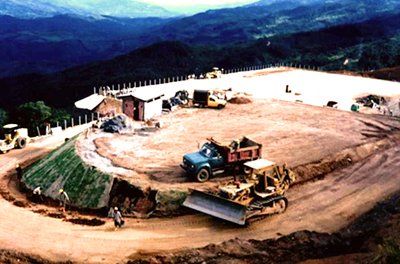 Una excavadora está moviendo tierra en un sitio de construcción con montañas al fondo