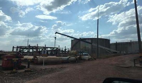 Un gran tanque está estacionado al costado de un camino de tierra.