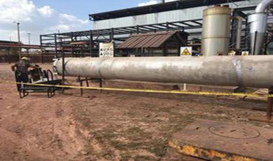 Un hombre está parado junto a una gran tubería en un campo.