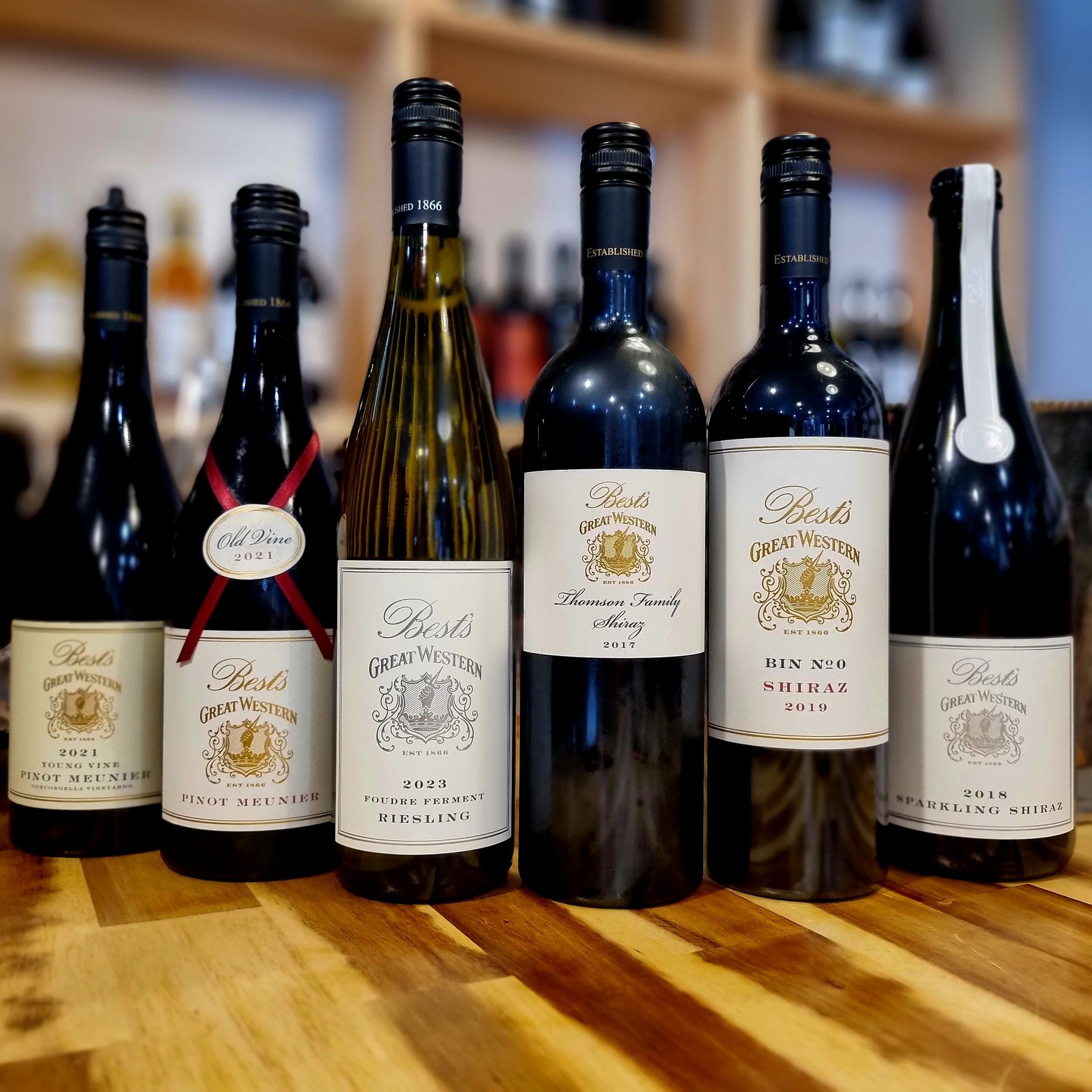 Several bottles of wine are lined up on a wooden table