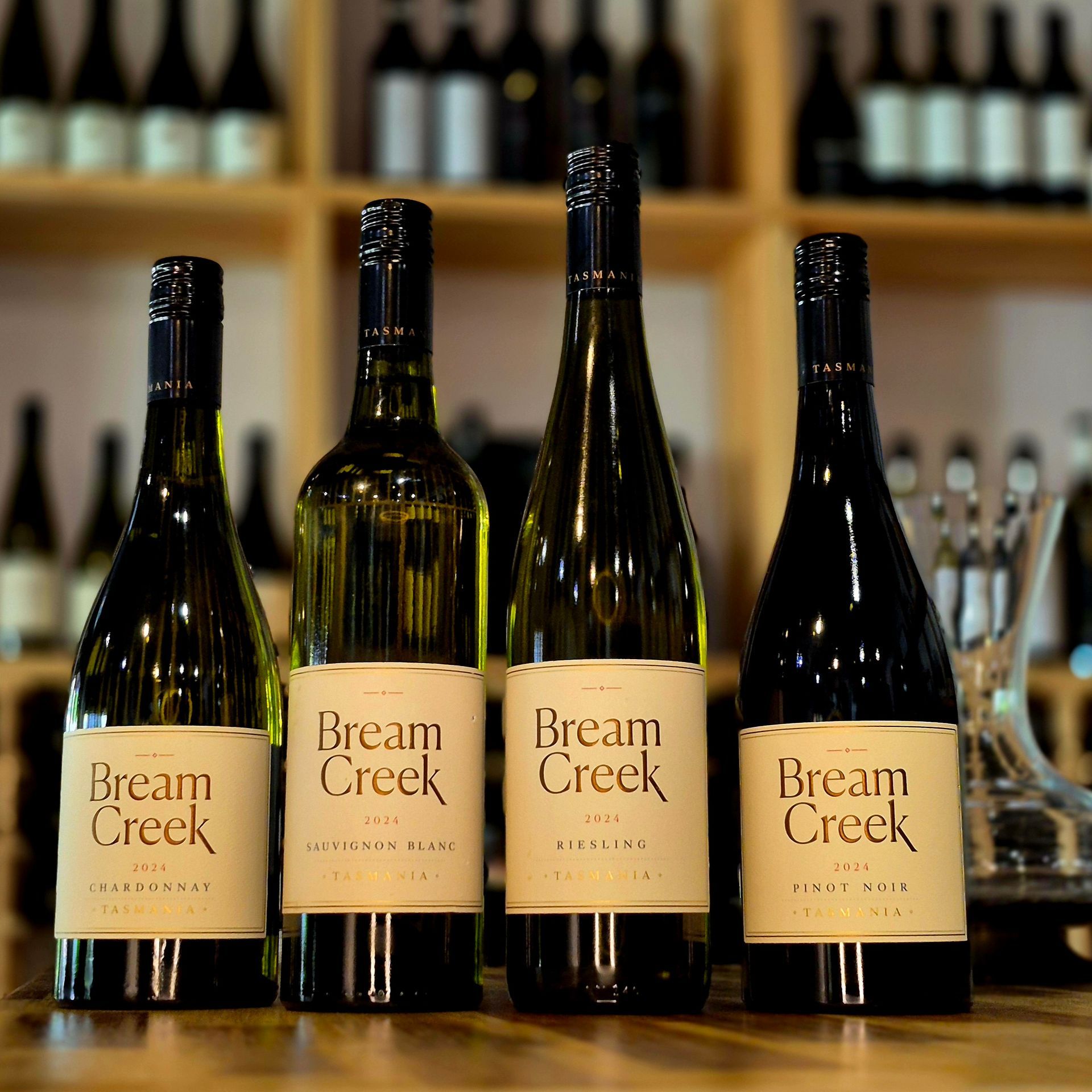 Three bottles of pipers brook wine are sitting on a wooden table