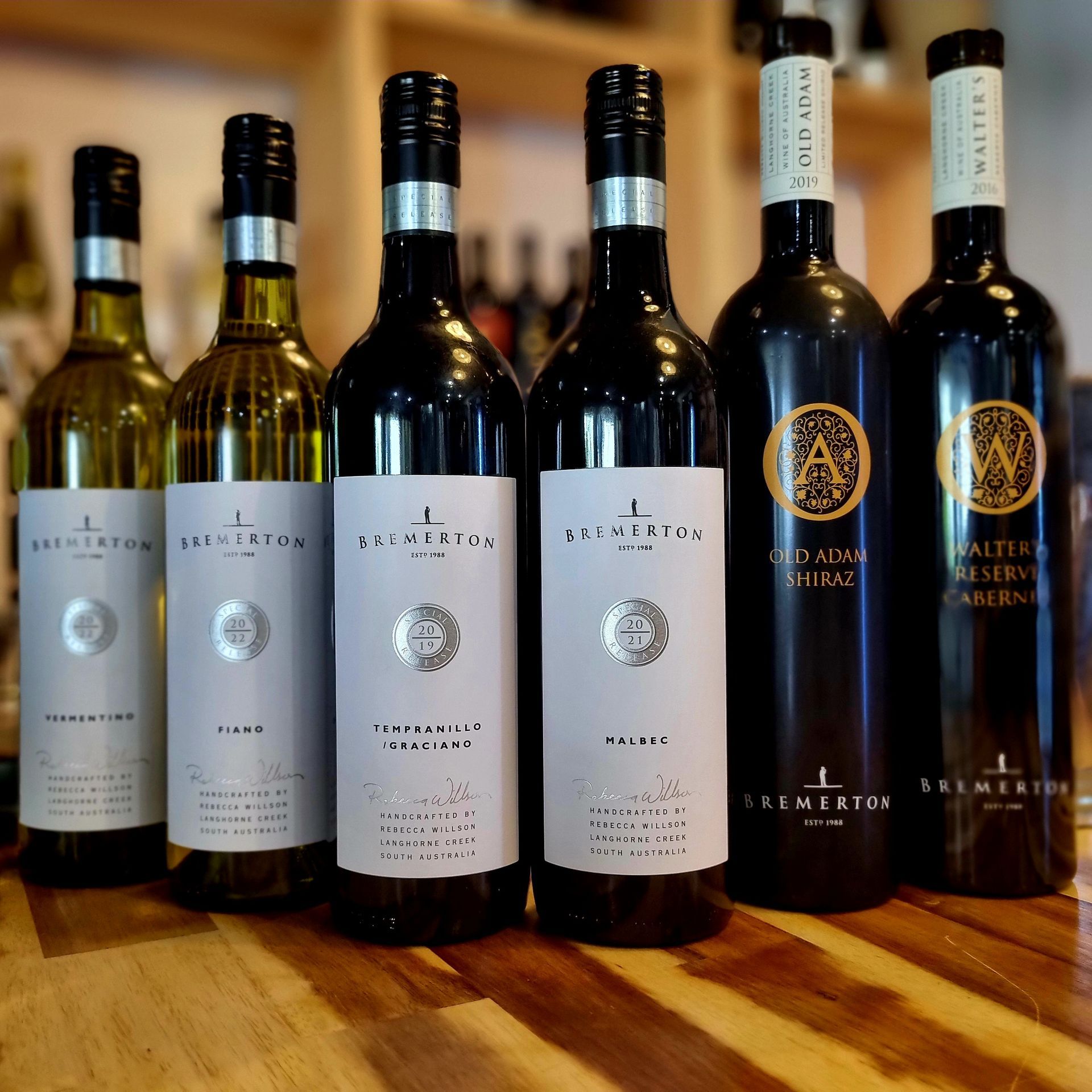 Several bottles of wine are lined up on a wooden table