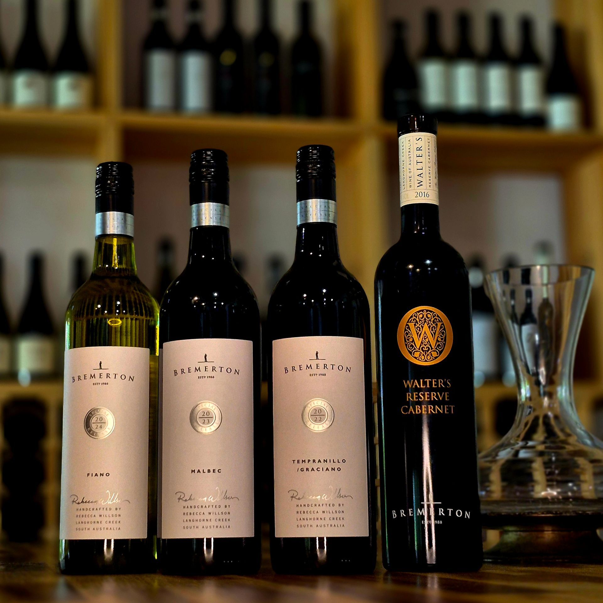Several bottles of wine are lined up on a wooden table