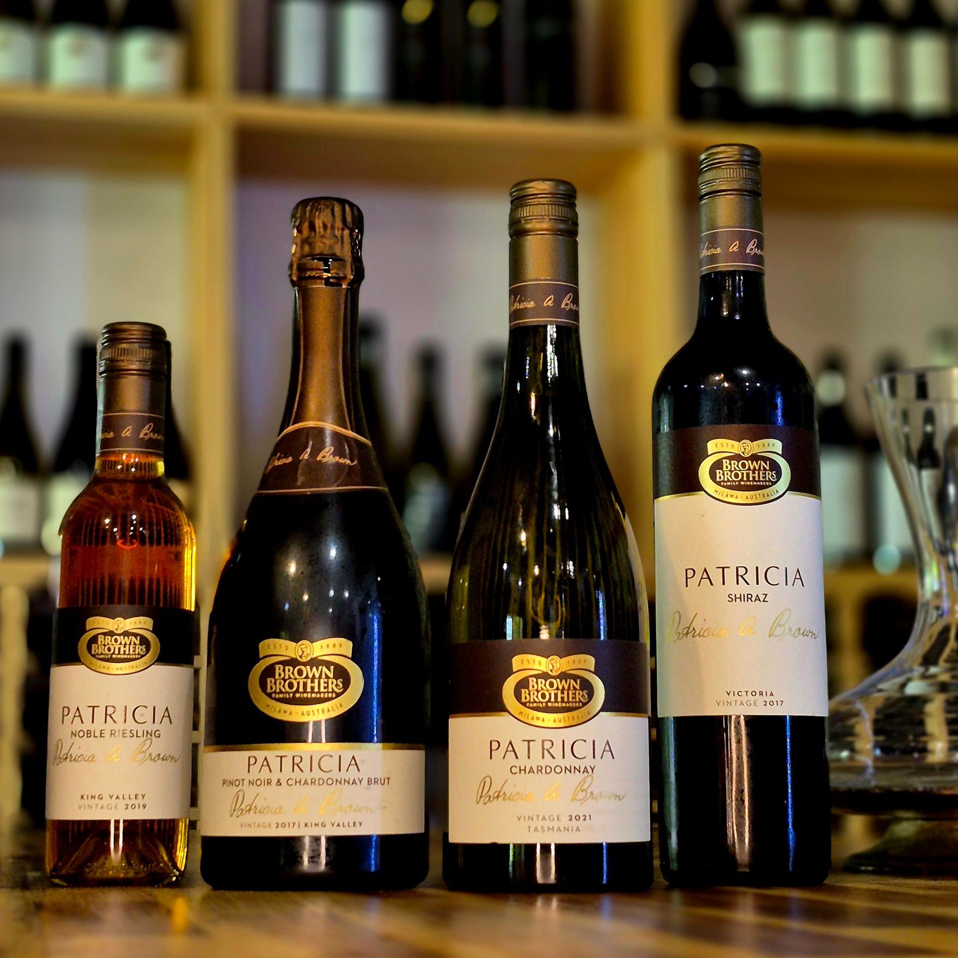 Five bottles of patricia wine are lined up on a wooden table