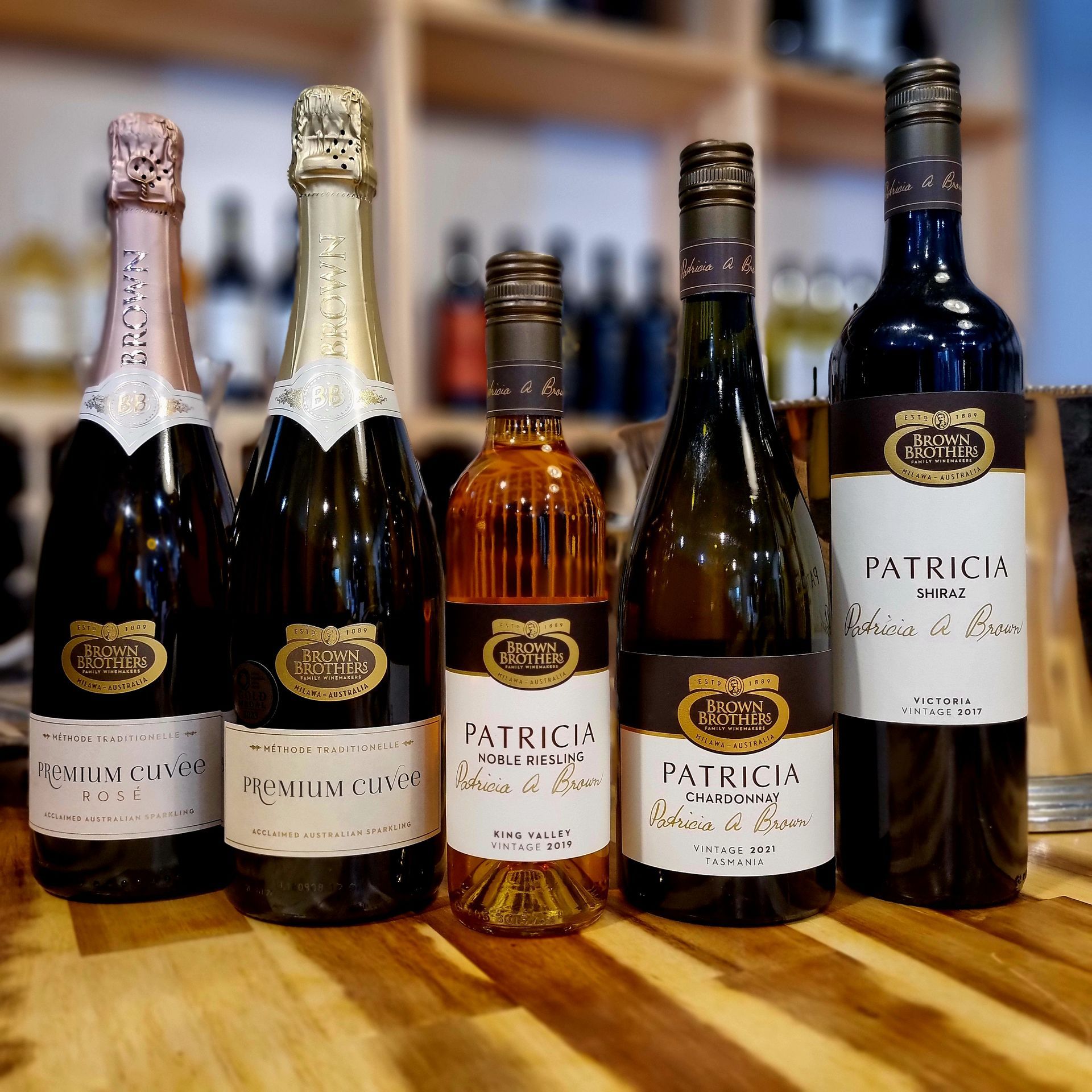 Five bottles of patricia wine are lined up on a wooden table