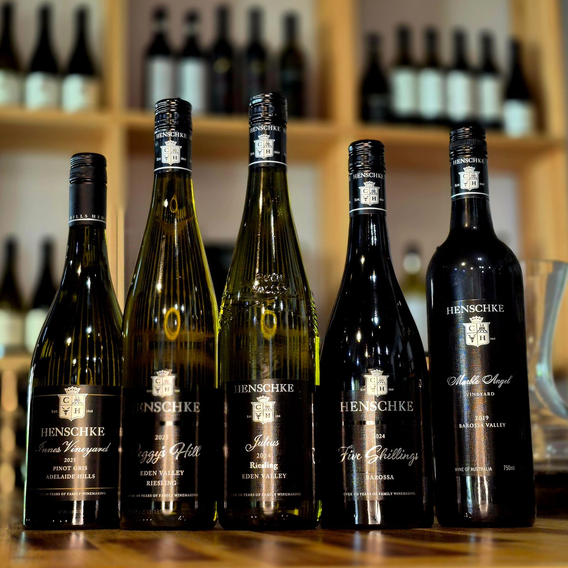 Several bottles of wine are lined up on a wooden table