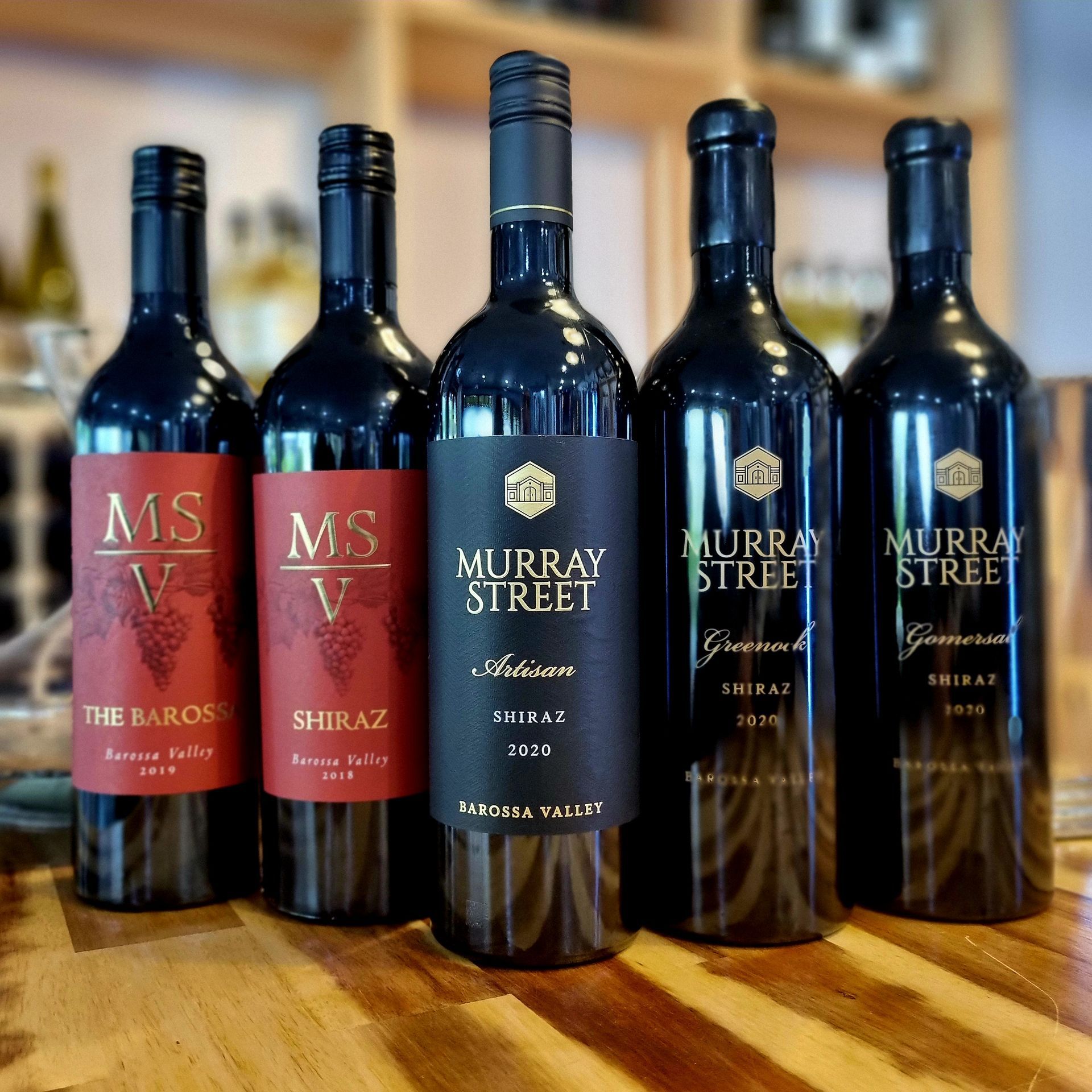 Five bottles of murray street wine are lined up on a wooden table