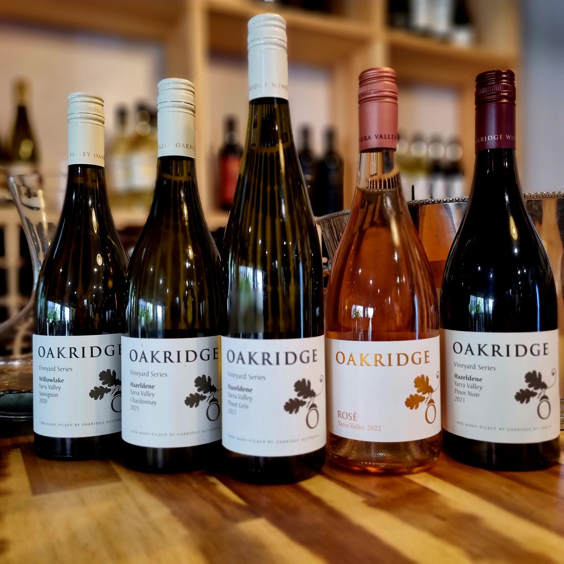 Oakridge wine bottles are lined up on a wooden table