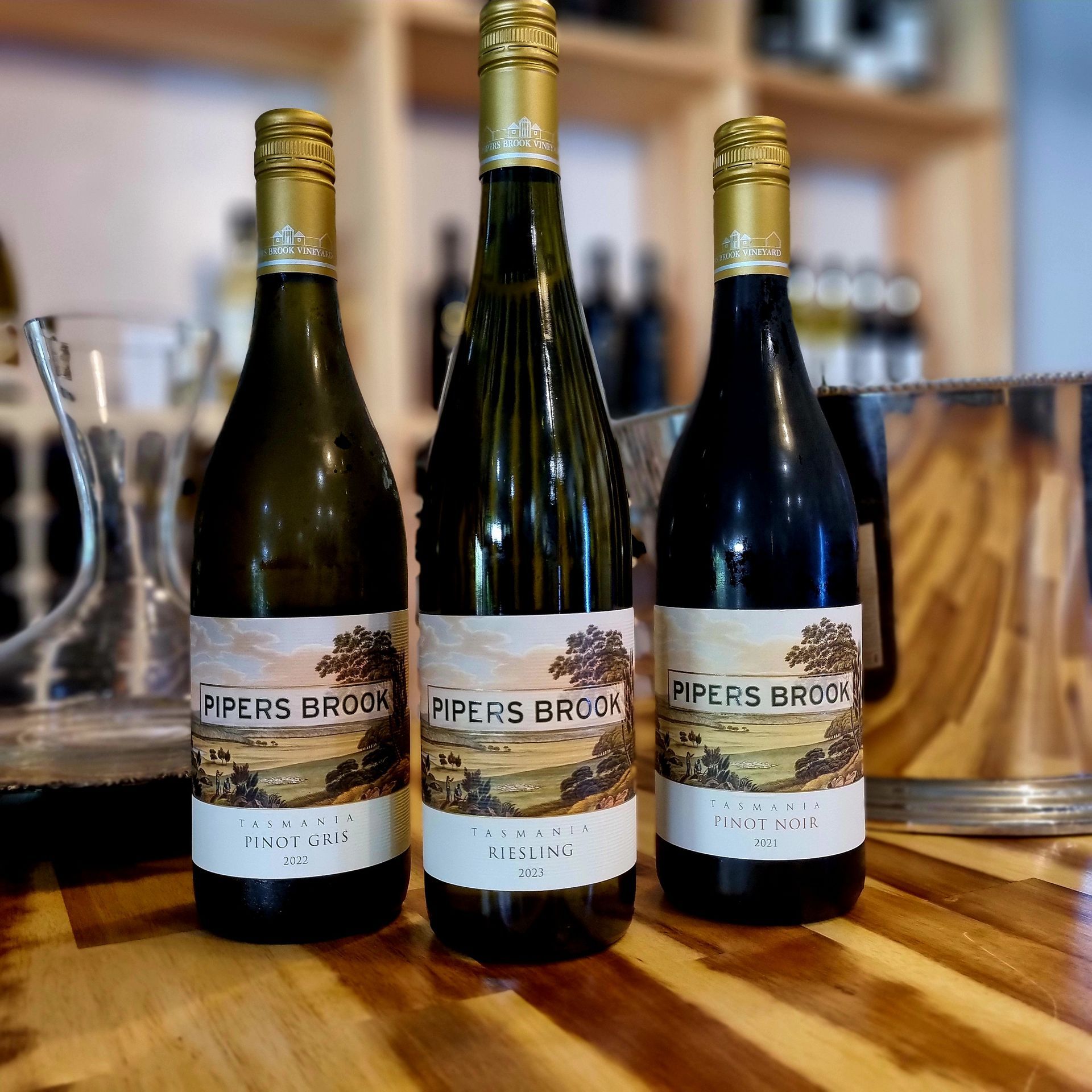 Three bottles of pipers brook wine are sitting on a wooden table