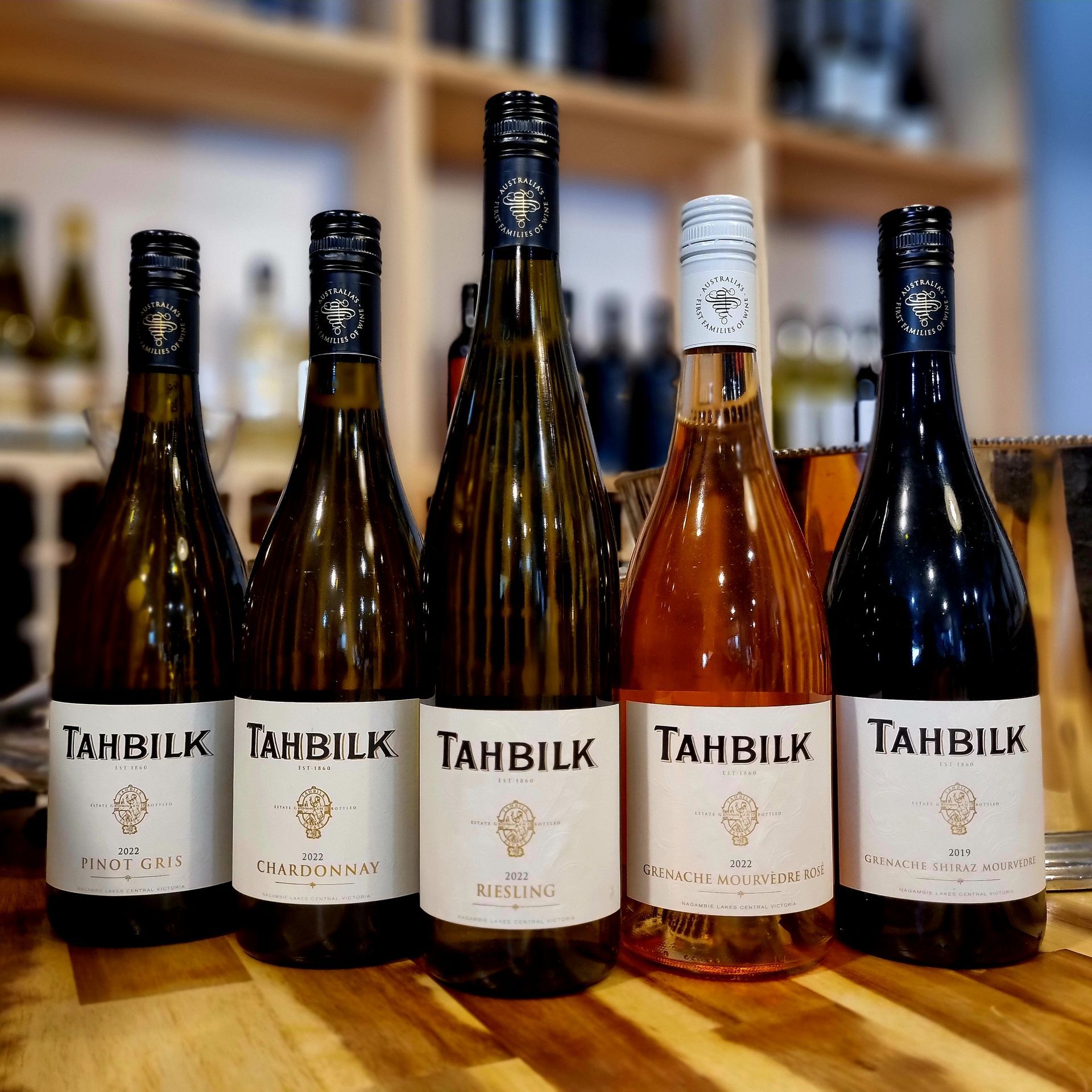 Bottles of tahbilk wine are lined up on a wooden table