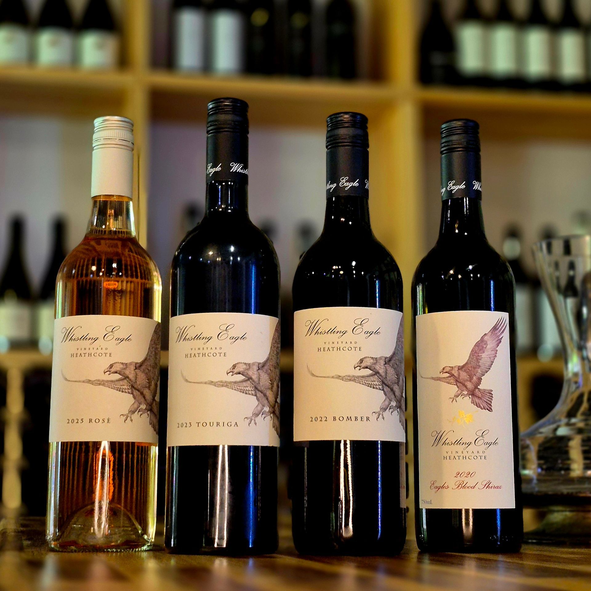 Five bottles of wine are lined up on a wooden table