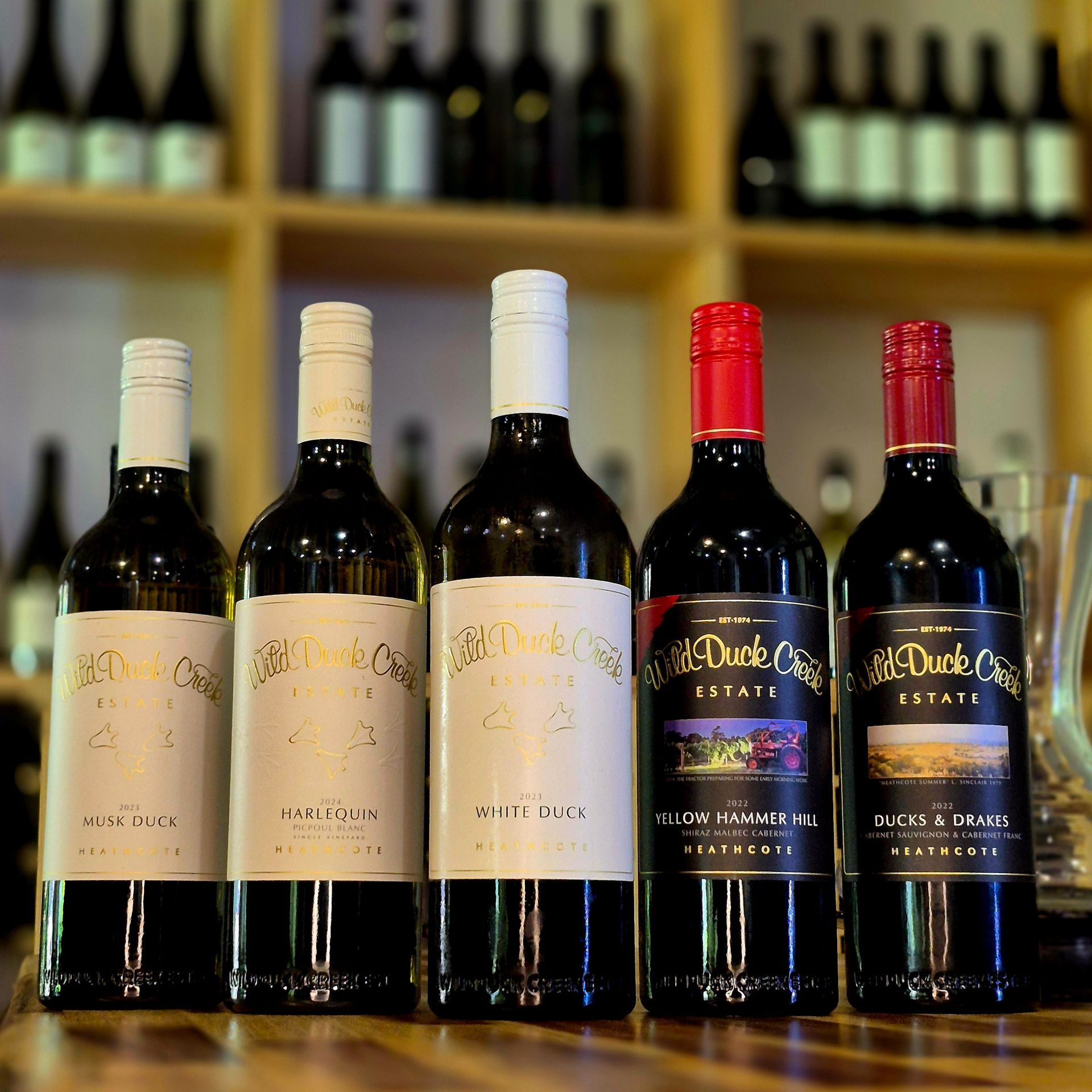 Bottles of tahbilk wine are lined up on a wooden table