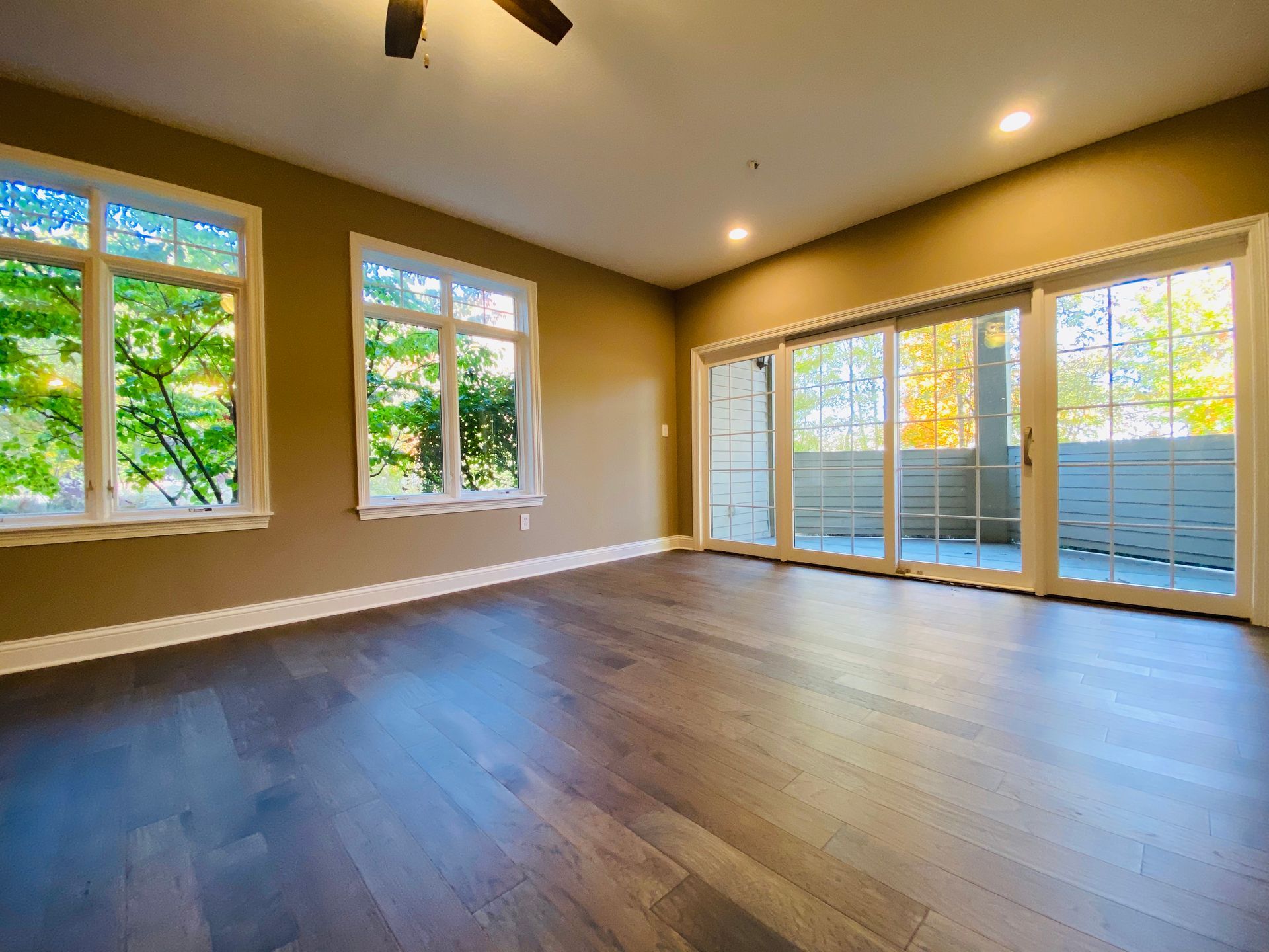 An empty living room with sliding glass doors and a ceiling fan.
