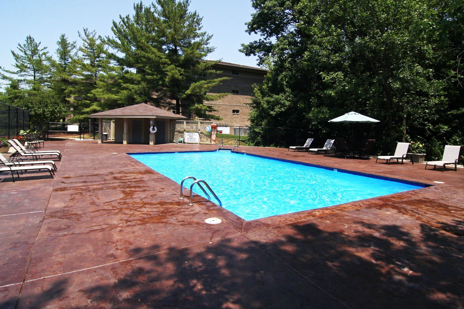 A large swimming pool surrounded by chairs and umbrellas