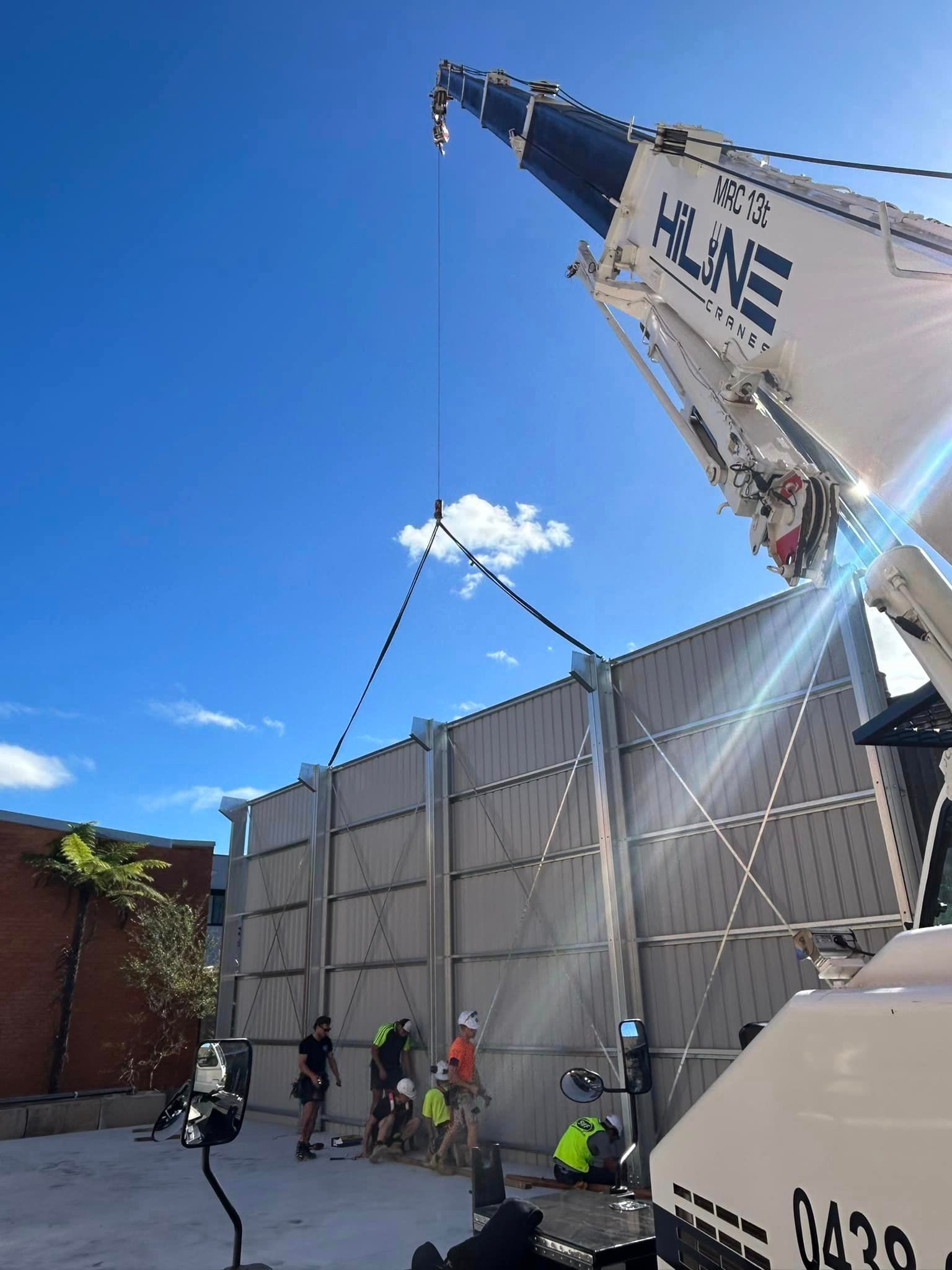 A crane is lifting a wall in front of a building.