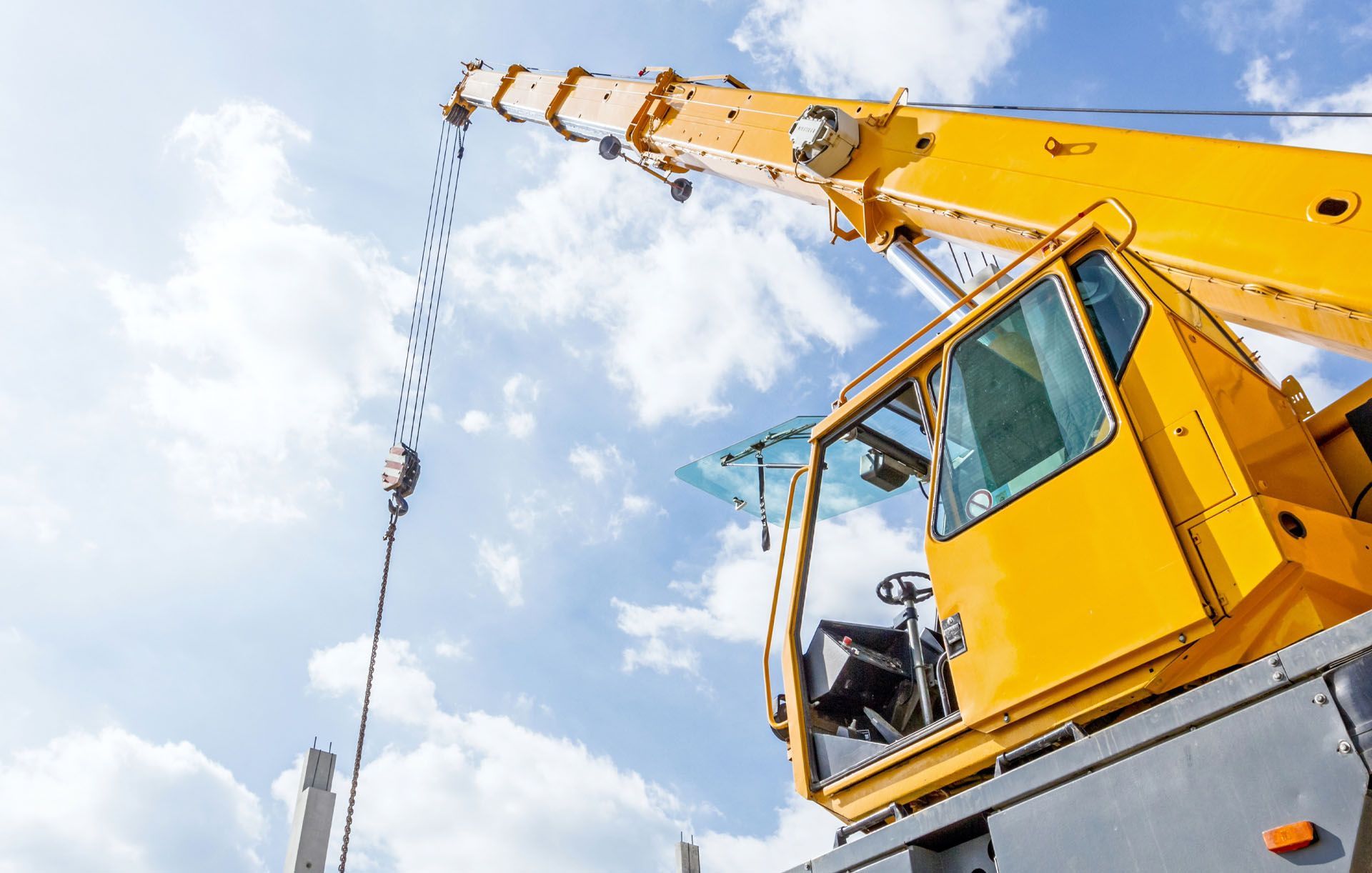 A close up of a yellow crane with a blue sky in the background.