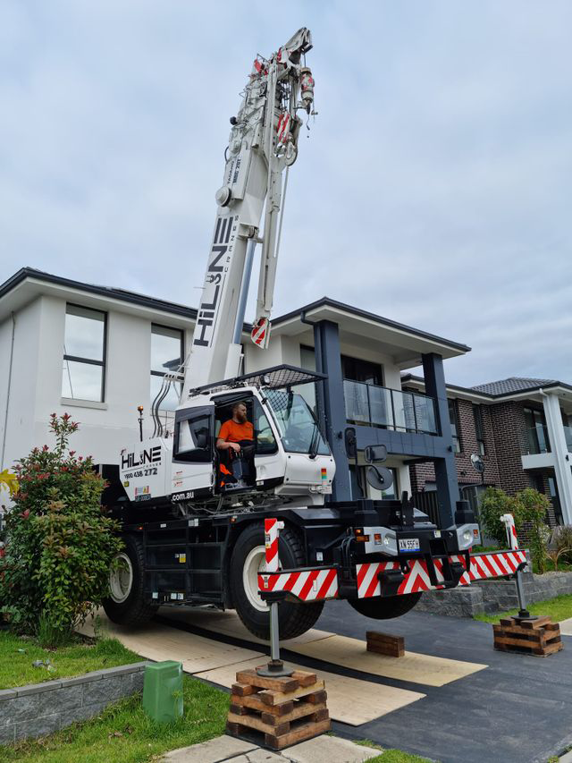 A large crane is parked in front of a house.