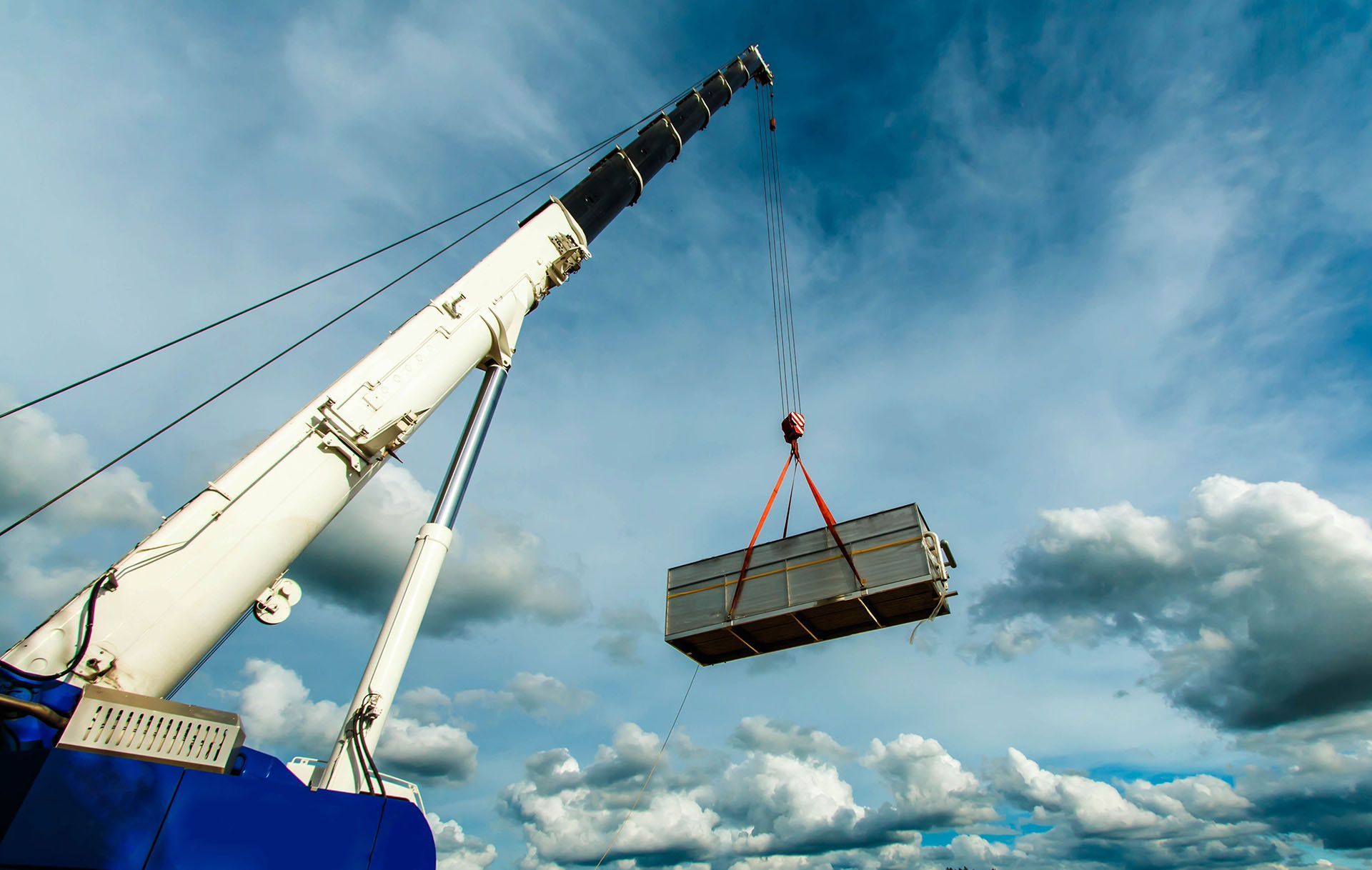 A crane is lifting a large piece of metal into the air.