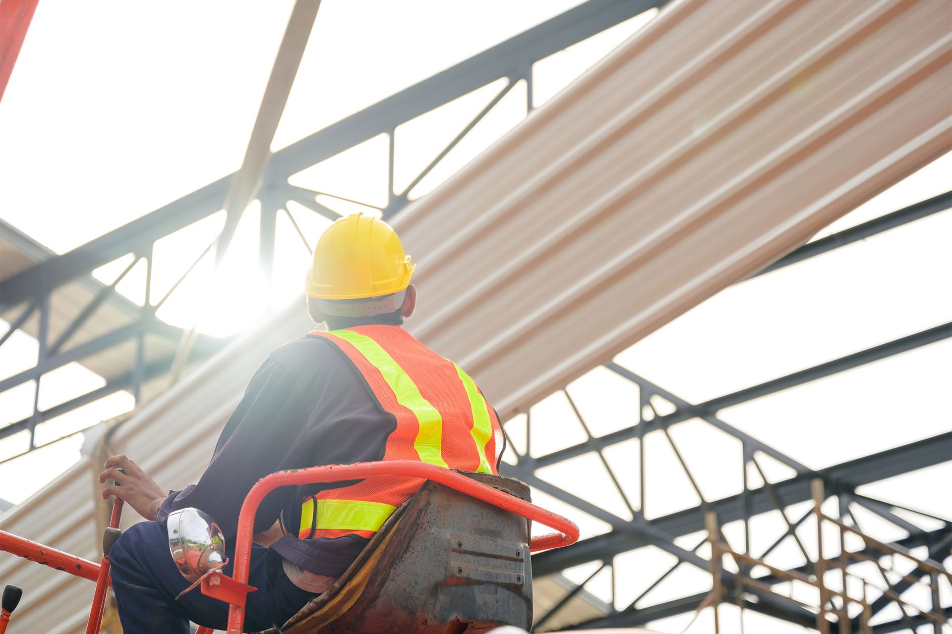 A construction worker is sitting on a lift working on a roof