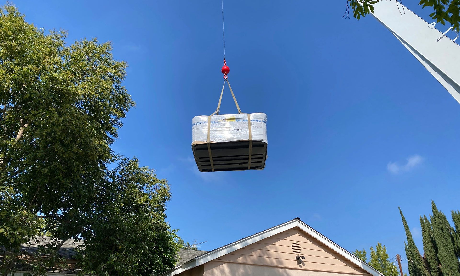 A hot tub is being lifted into the air by a crane.