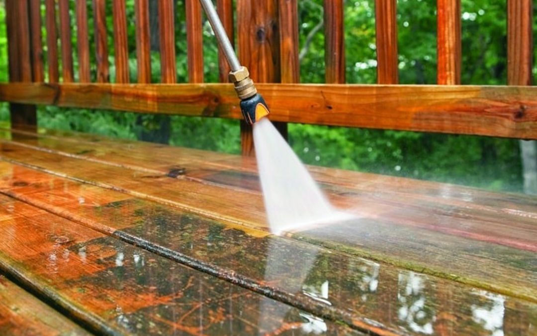 A power washer cleaning an outdoor wooden deck.
