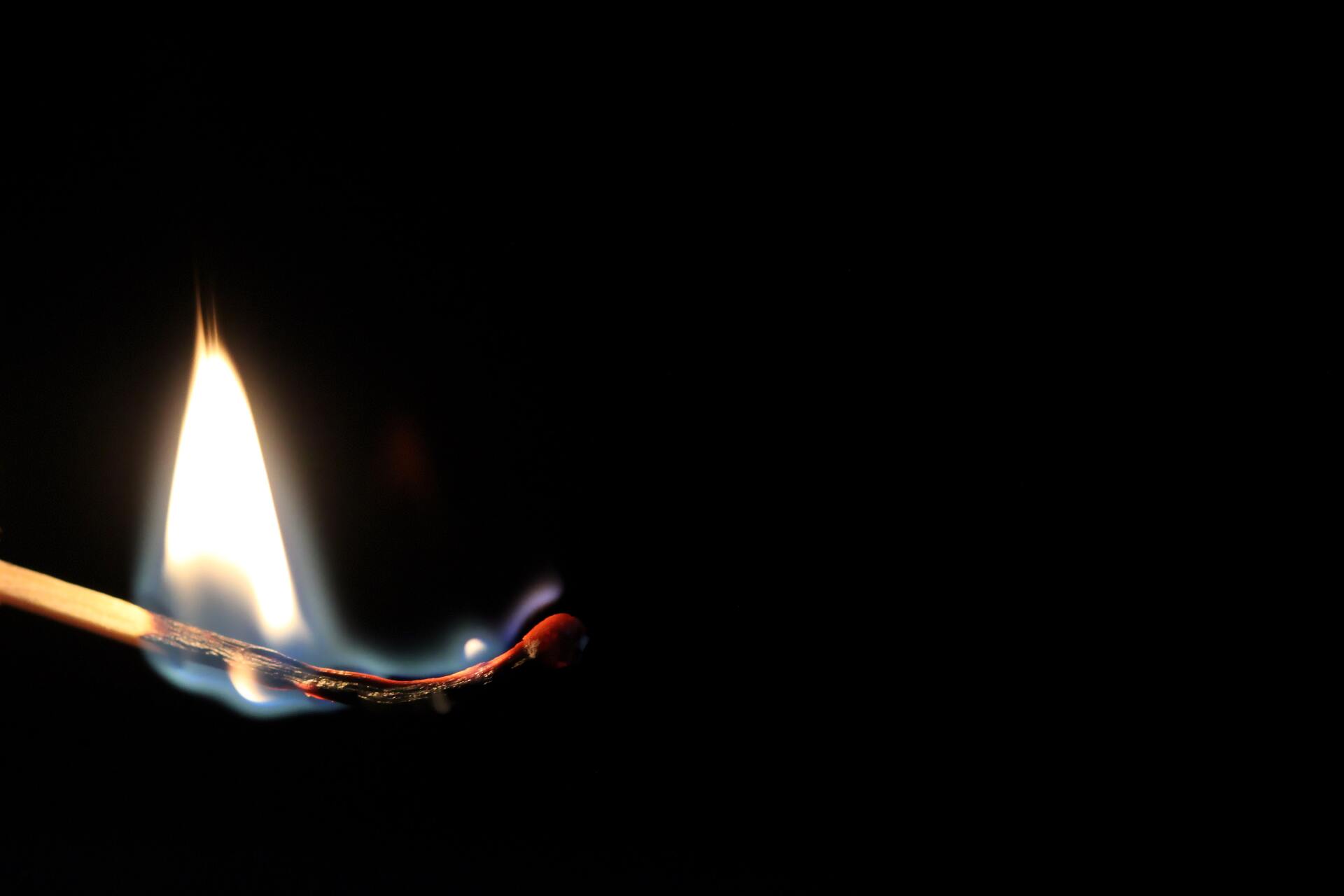 Matchcburning flame in darkness.