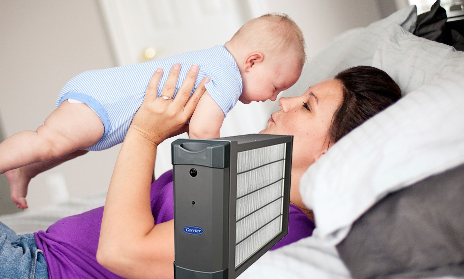 A woman is laying on a bed holding a baby.