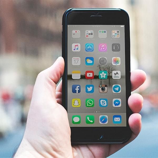 A person is holding a cell phone in their right hand