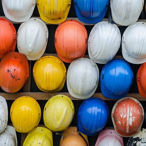 Many different colored hard hats are lined up on a shelf