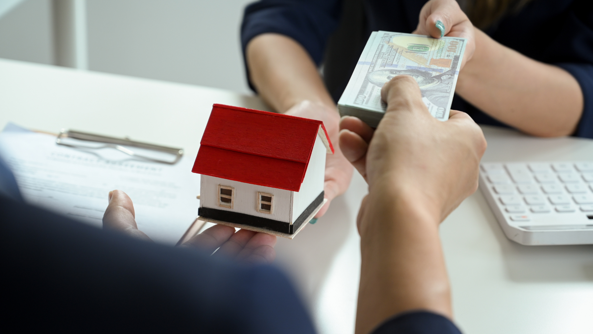 A man is handing a woman a model house and money.