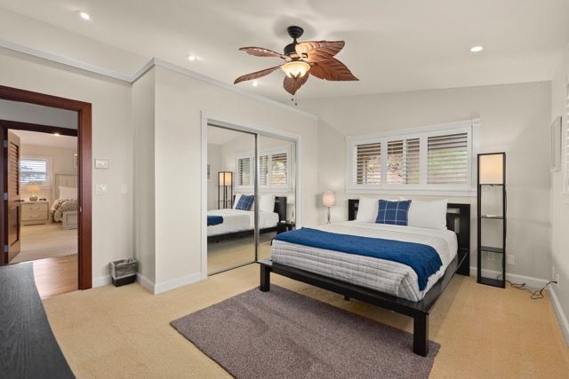 A bedroom with a large bed and a ceiling fan