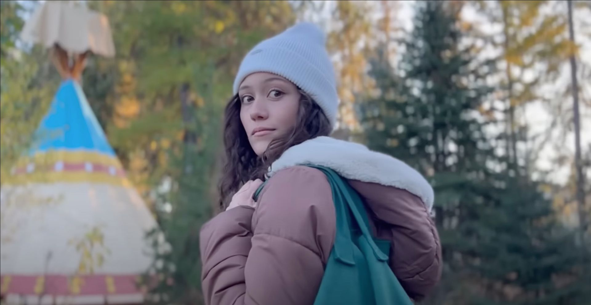 A woman in a hat is heading towards the glamping tipi