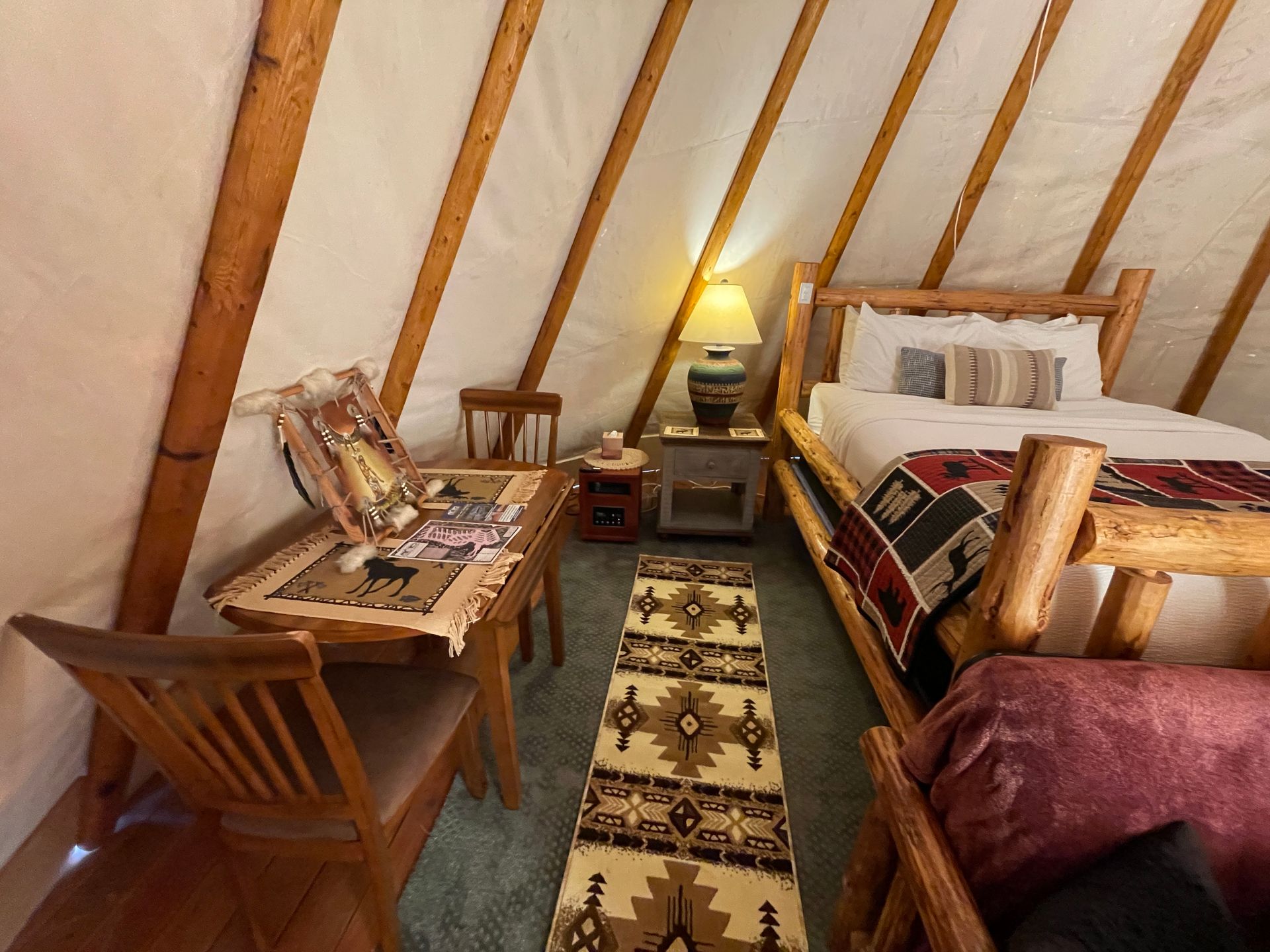 Interior of glamping tipi with queen bed and dining table