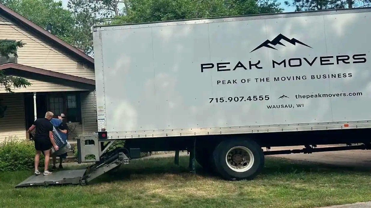 A white moving truck is parked in front of a house.