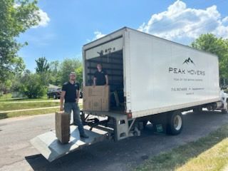 Two men are standing in front of a moving truck.