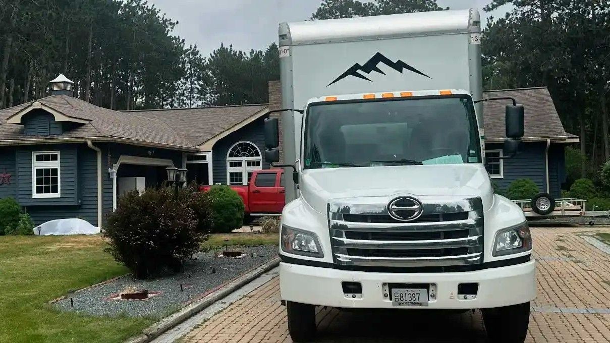 A white moving truck is parked in front of a house.