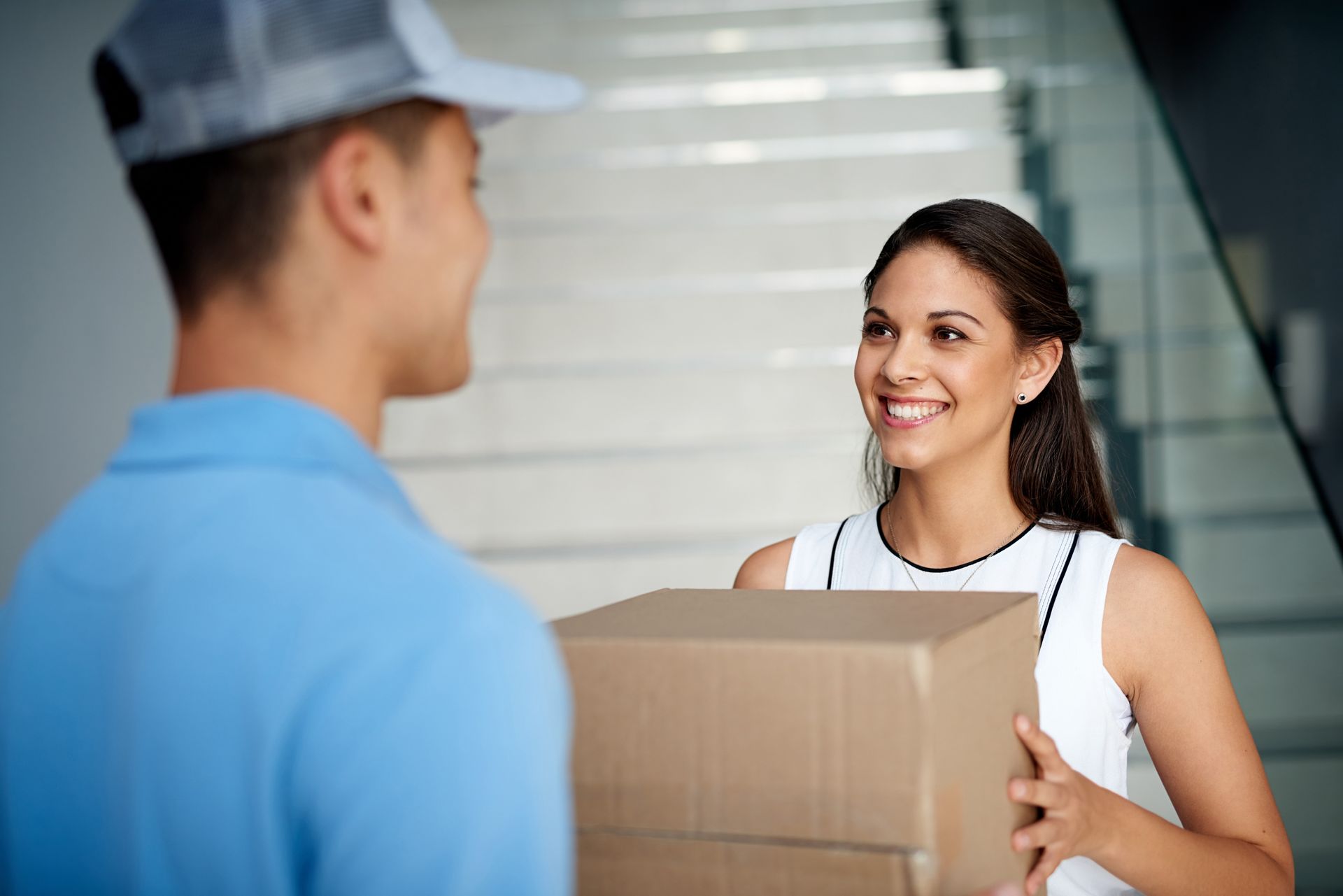 A woman is receiving a box from a delivery man.