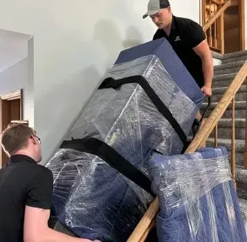 A man is pushing a large box up a set of stairs.