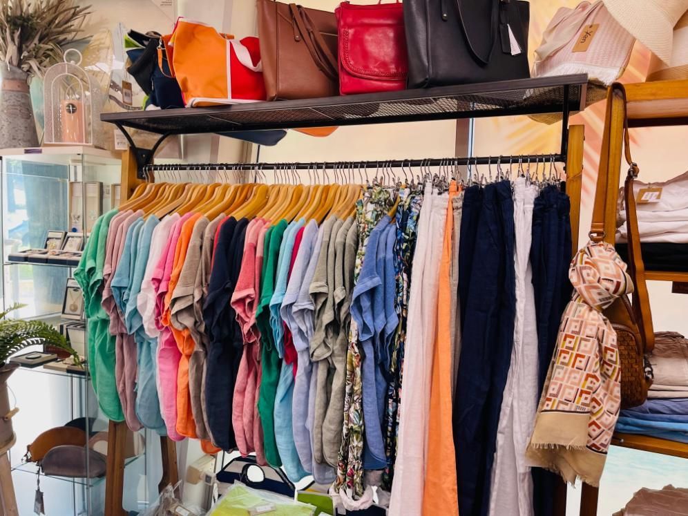 A Store Filled With Clothes And Bags Hanging On Racks — Beach Time Trading Co In Yeppoon, QLD