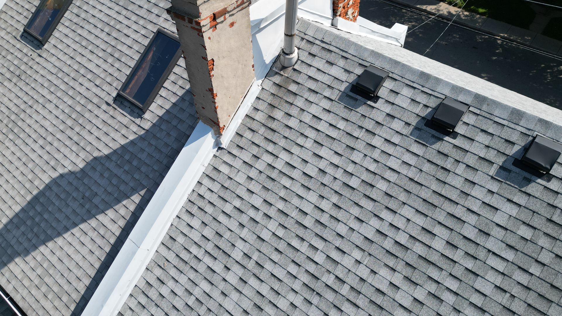 An aerial view of a roof with a chimney and skylights