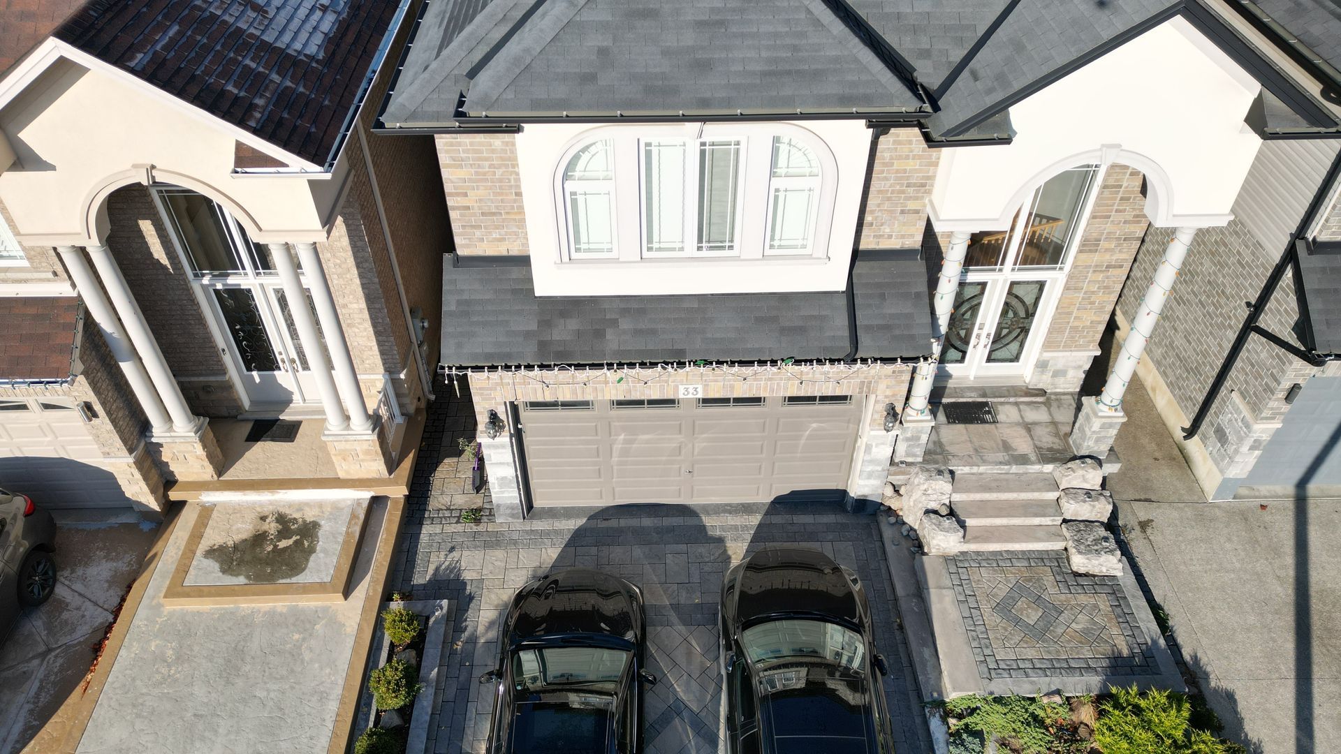 An aerial view of a house with two cars parked in front of it
