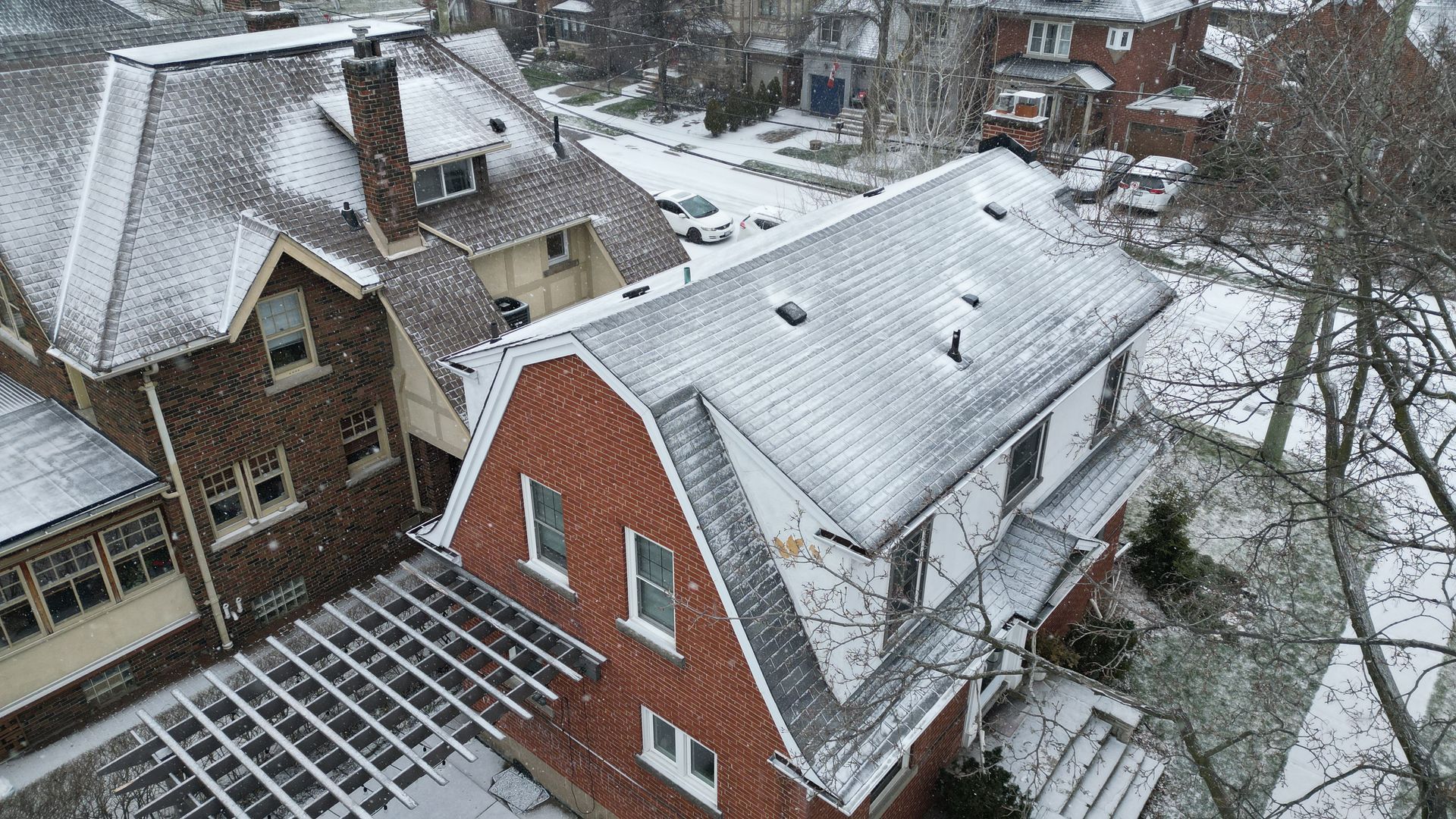 An aerial view of a brick house covered in snow