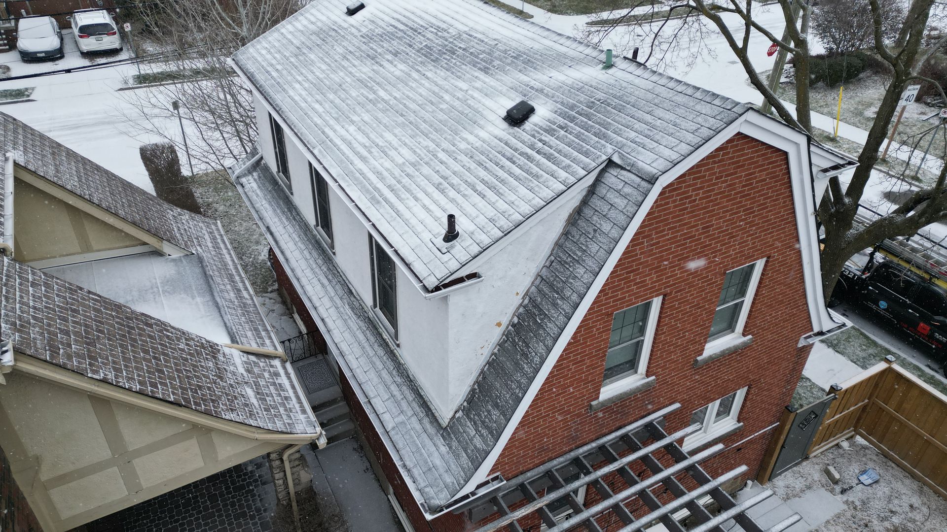 An aerial view of a brick house with snow on the roof