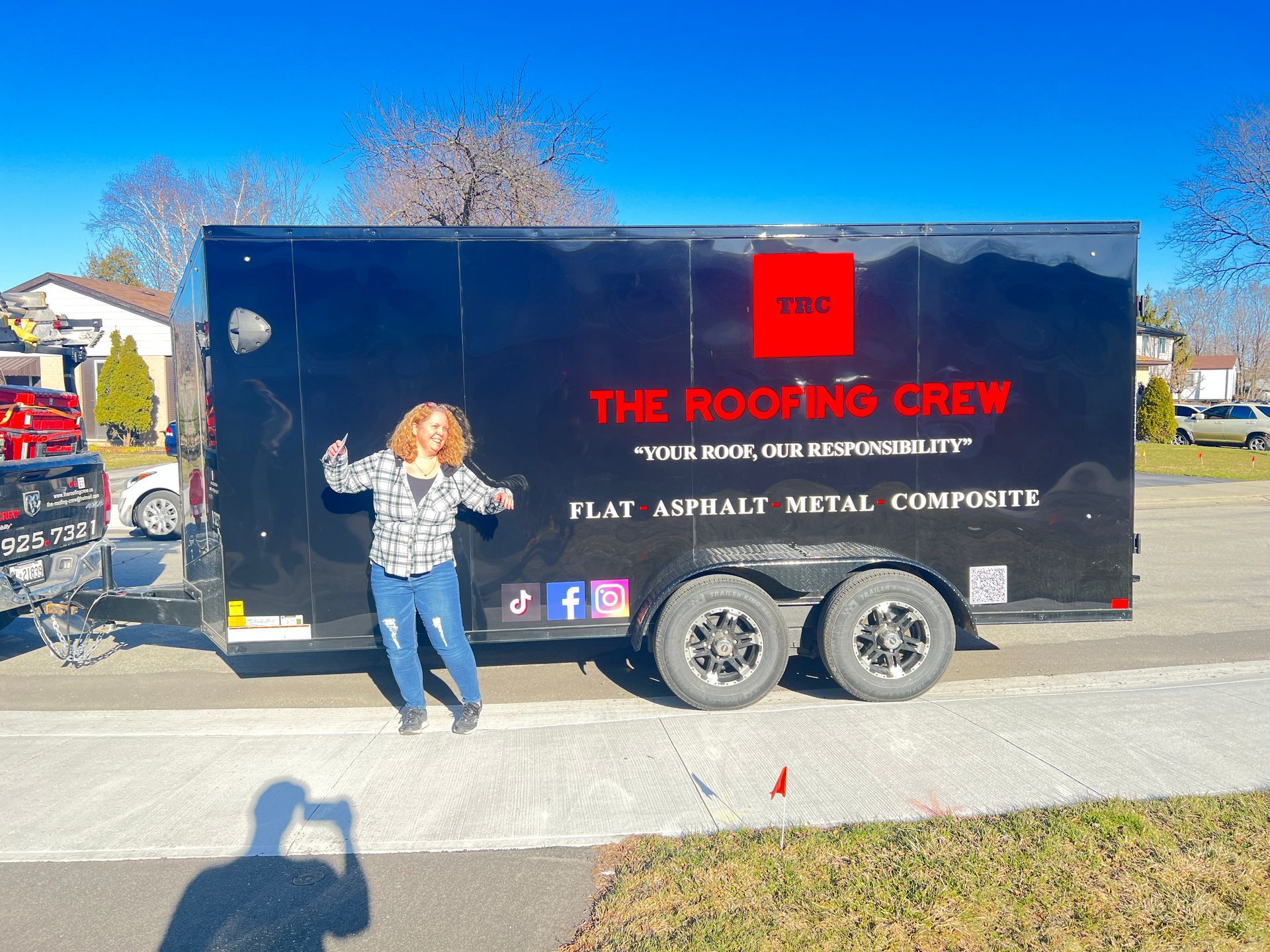A woman stands in front of a trailer that says the roofing crew