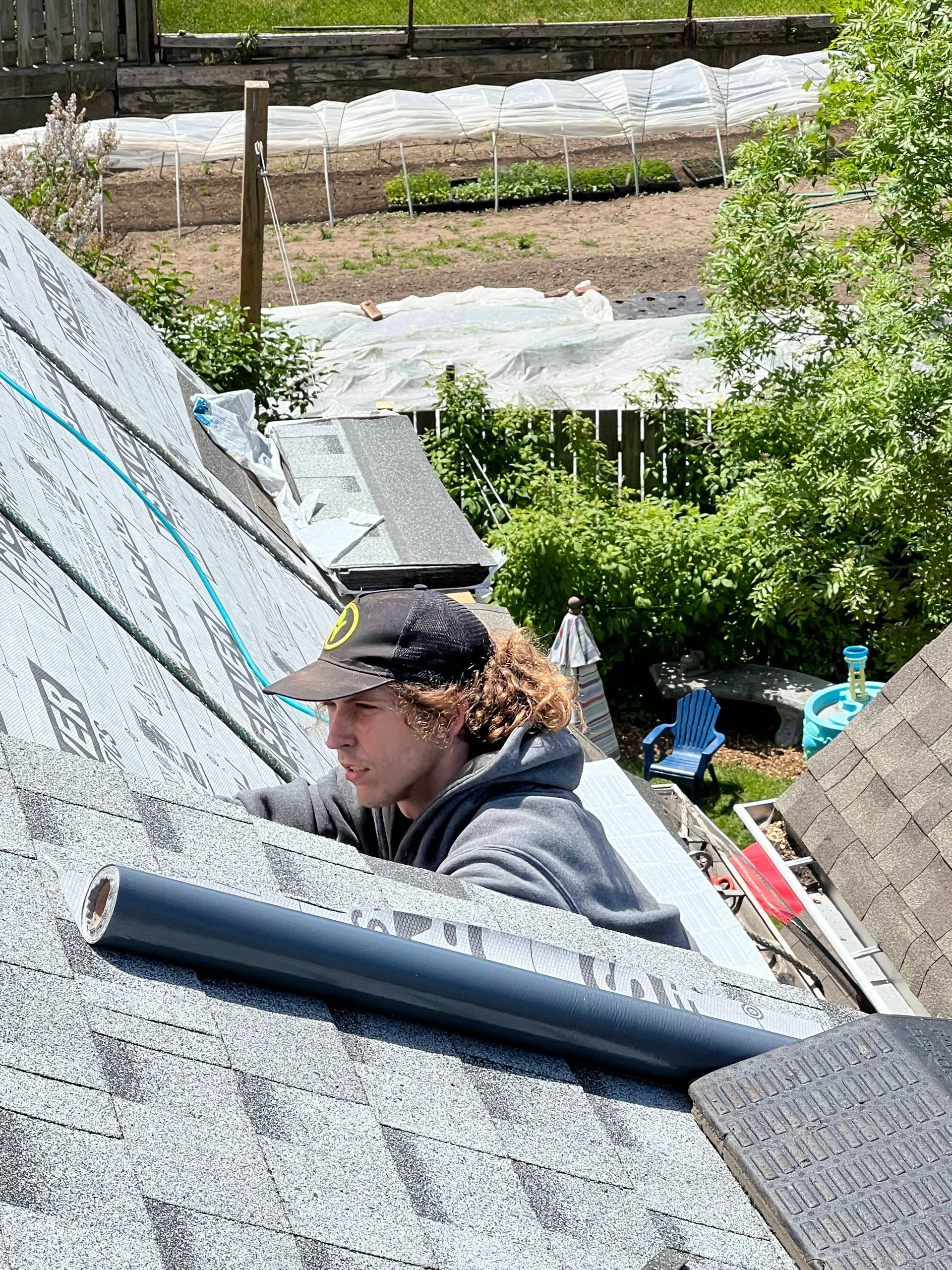 A man with curly hair is working on a roof